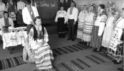Elder braidsmaid braiding the braid's hair while other braidsmaids sing