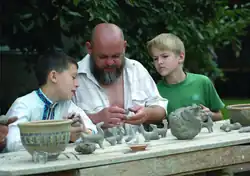 A man teaching boys how to make clay toys