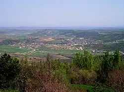 Image of village in the distance, taken from a green hill nearby