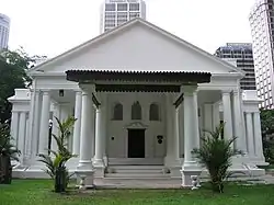 The church's entrance features heavy two-leaf timber doors framed by moulded semi-circular pediments.