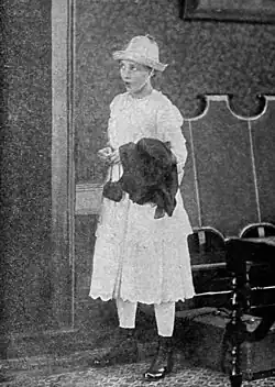 Black and white film still showing a woman in period dress inside a castle setting