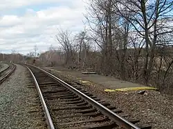A disused railway platform next to an active rail line