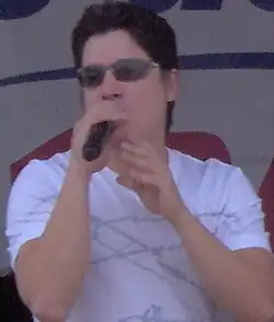 A man wearing sunglasses and a white shirt is performing on stage.