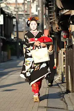 An apprentice wearing formal black kimono and tall sandals