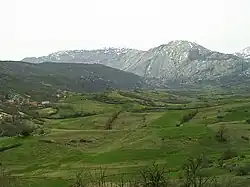 Panorama of green fields with rugged mountains in the background