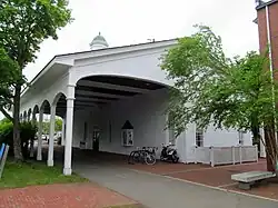 A paved bike path passing under an open but roofed section of a former train station