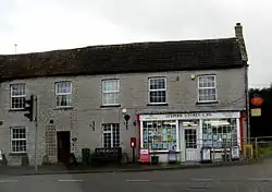 Small shop with white surrounds to the windows set in the right hand building of a terrace.