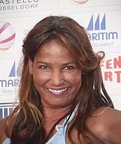 Abd el Farrag with brown hair wearing a blue bikini top. She is smiling wide.