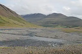 a shallow river following through a rocky valley floor