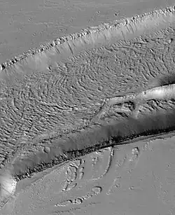 The Olympica Fossae, as seen by HiRISE. Click on image to see rock layers in wall. Image is located in Tharsis quadrangle.