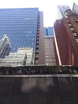 The facade as seen from 54th Street. Most of the facade is made of green glass, but there is a masonry "spine" visible at center right.