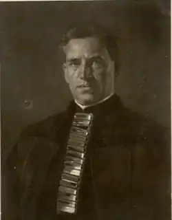 A man wearing formal ceremonial vestments with metallic rectangles down the front