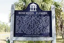 A color photograph of the front of the bronze plaque in Rosewood next to the highway