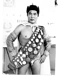 A half naked man with a sash full of medallions