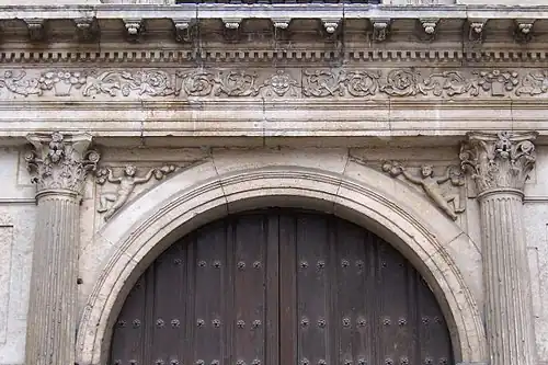 In the spandrels of the arch of entrance there are two ornamental figurines that represent some boys or sand devils that hold some fruits.