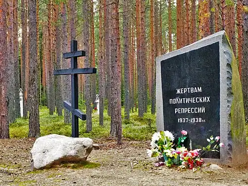 A monument, Orthodox cross and flowers in a forest