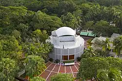 Aerial photo of a large, round, white building surrounded by trees