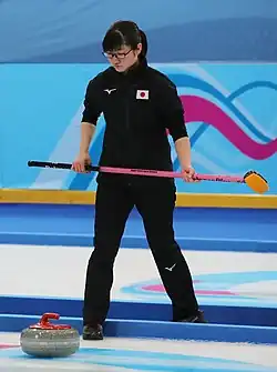 Momoha Tabata holds a broom while looking down at a curling stone
