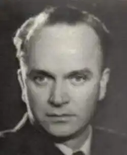 Sepia studio publicity shot of a clean-shaven man with serious expression, strong features and receding, short hair