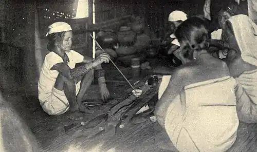 A 1922 photograph of a shaman of the Itneg people renewing an offering to the spirit (anito) of a warrior's kalasag