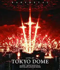 A series of orange-yellow pyrotechnics stand out in a group of three, shaped like crosses, above a group of buildings with a dark, red sky; "BABYMETAL" appears at the top, and "LIVE AT", "TOKYO DOME", "BABYMETAL WORLD TOUR 2016", "LEGEND -METAL RESISTANCE-", and "RED NIGHT & BLACK NIGHT" appear at the bottom, all in white, all caps text.