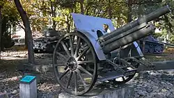 An artillery piece mounted on a concrete platform in a park