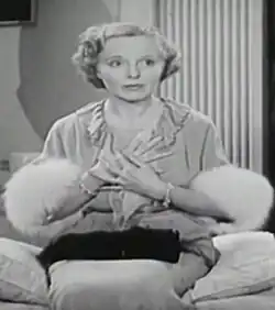 A white woman with blond hair, seated at a table