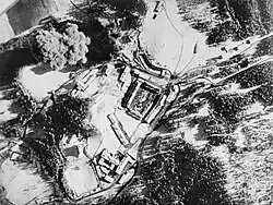 Black and white aerial photograph of buildings and smoke