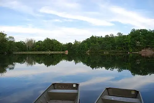 A lake with green trees in the background reflecting upon the water.