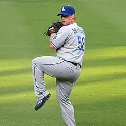 A man in a gray baseball uniform and blue cap