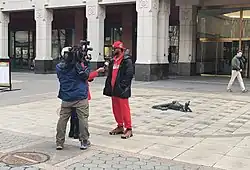 Two reporters, one with a camera, interview Smalls in front of the NLRB building, where the votes were counted.