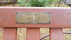 A plaque on a bench with the text "'Have a seat pet' Annie Inglis MBE 1922 - 2010"