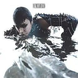 A picture of Lovato coming out of the water with dark makeup and an all-black outfit with spikes and chains.