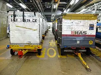 Those on the left are dollies from Cathay Pacific for baggage unit load devices (ULDs). Those on the right are dollies for loose baggage.