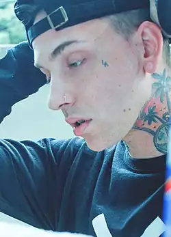 A picture of Blackbear with his cap on, exposing his neck tattoo