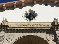 Inscription above the main entrance: "Dios nos dio los campos. El arte humana edificó ciudades." This translates to "God gave us the fields. Human art built cities."