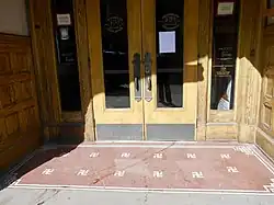 a terracotta floor with white tiles outlining multiple small, counter-clockwise swastika patterns.
