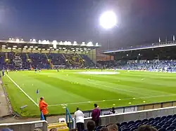 Fratton Park football stadium at night, home of Portsmouth F.C. The pitch is lit by floodlights.