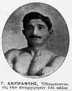 Black and white circular headshot photo of a topless man with thick black hair and a thick black moustache