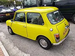 A small yellow car stuck in a traffic jam