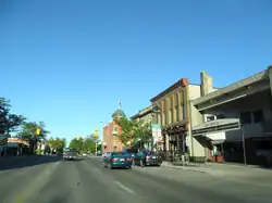 A road travels through a Main Street, with wall-to-wall buildings under a blue sky