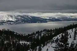 Photo of a large lake surrounded by mountains under heavy cloud cover