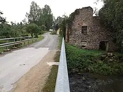 A road, an abandoned building with overgrown vegetation.