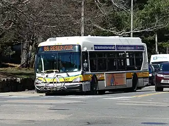A white and yellow transit bus on an urban street