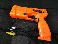Chunky, bright orange light gun with black RCA cables attached
