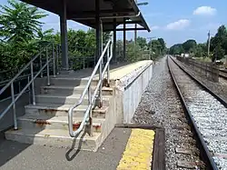 A section of high-level railway platform. The section of platform edge nearest the track is missing, with some damage to the concrete visible