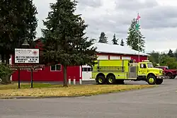 A sign for a fire station, with the building behind it.