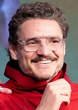 Pedro Pascal smiling to the right