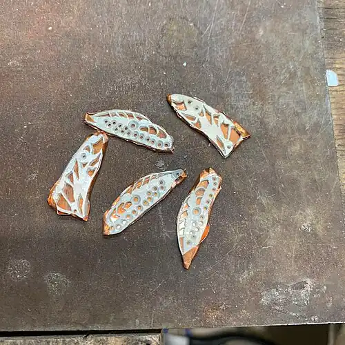 5. The piece and the mica sheet are carefully wrapped in the copper foil. The copper folds must not touch the parts that will be enamelled.