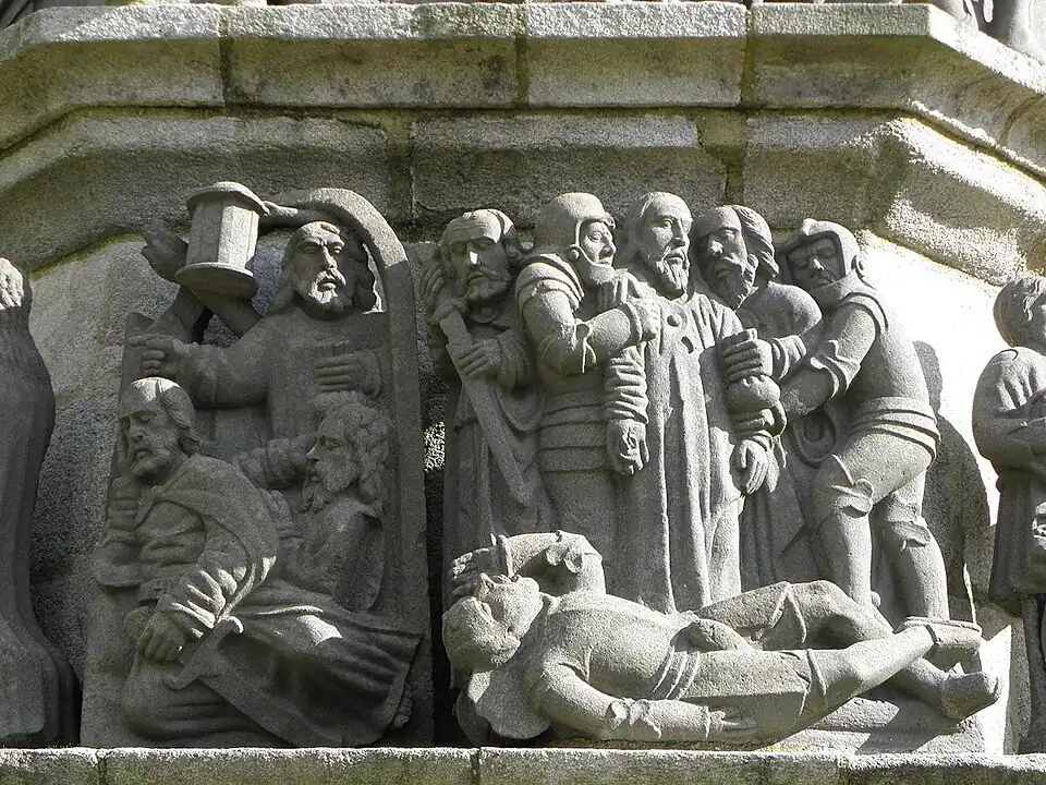 Jesus' arrest.This sculpture on the Plougonven calvary's south side depicts Jesus' arrest. On the left is Judas Iscariot holding a purse and below him an apostle sleeping, whilst a second, St Peter is also asleep his hand on his sword. Then is Judas embracing Jesus to identify him. He is held by two guards. St Peter now puts his sword back in its sheath having struck Malchus who lies on the floor